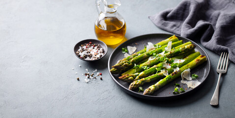 Roasted asparagus with parmesan cheese. Grey background. Copy space.