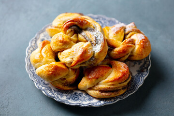 Cinnamon and cardamon buns, rolls, Kanelbullar on a tea plate. Grey background. Close up.