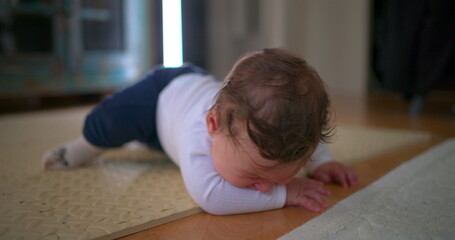 Baby lying face down on the floor, visibly upset and crying, expressing frustration and discomfort...