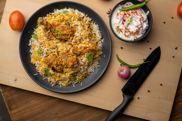 Spicy chicken biryani in pot. served with onion raita	