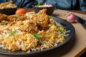 Spicy chicken biryani in pot. served with onion raita	