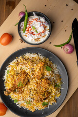 Spicy chicken biryani in pot. served with onion raita	