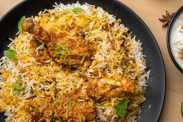 Spicy chicken biryani in pot. served with onion raita	