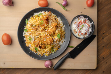 Spicy chicken biryani in pot. served with onion raita	