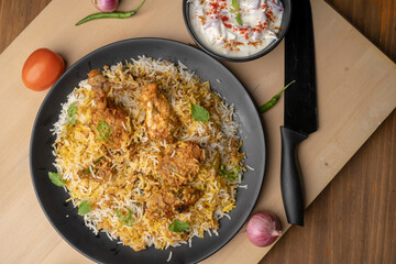 Spicy chicken biryani in pot. served with onion raita	