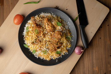 Spicy chicken biryani in pot. served with onion raita	