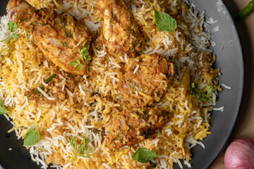 Spicy chicken biryani in pot. served with onion raita	
