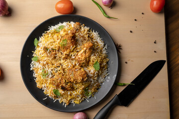 Spicy chicken biryani in pot. served with onion raita	