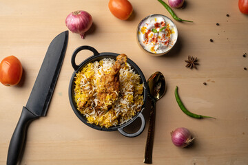 Spicy chicken biryani in pot. served with onion raita	