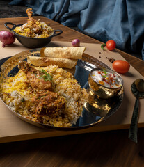 Spicy chicken biryani in pot. served with onion raita	