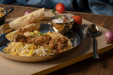 Spicy chicken biryani in pot. served with onion raita	