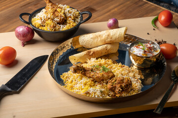 Spicy chicken biryani in pot. served with onion raita	