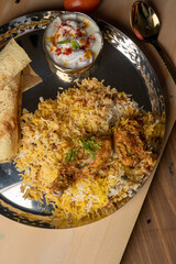Spicy chicken biryani in pot. served with onion raita	
