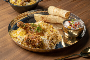 Spicy chicken biryani in pot. served with onion raita	