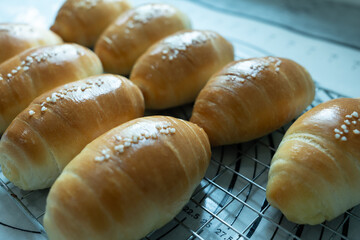 Freshly baked golden bread rolls cooling on a wire rack, topped with coarse sugar crystals.