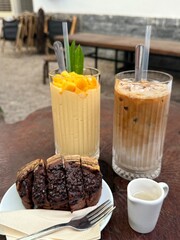 vertical photo banana bread two drinks iced latte Delicious mango float cake in glasses on wooden board. Filipino sweet cuisine