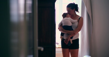 Mother holding her baby close in a softly lit room, showcasing a tender moment of caregiving and connection, highlighting love and nurturing in a calm environment