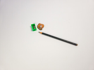 Close up of a pencil, sharpener, and pencil shavings on a white background