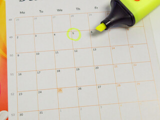 Calendar with a highlighted date and a yellow highlighter pen