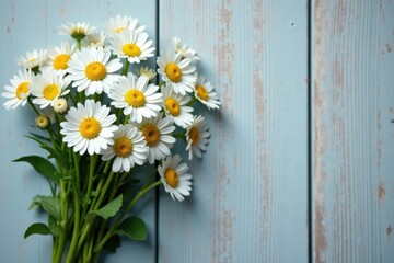 Obraz premium A charming bouquet of fresh daisies rests against a rustic light blue wooden background, creating a serene and peaceful floral arrangement.