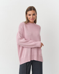 Fashionable woman models a soft pink sweater in a bright studio setting