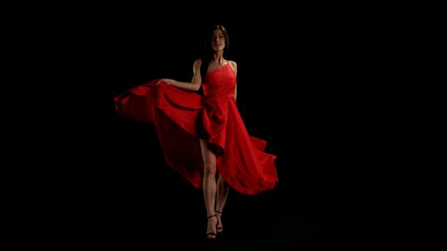 Brunette Woman in Ruby Red Dress Posing Against a Black Background . Filmed on High Speed Cinematic Camera in Super Slow Motion