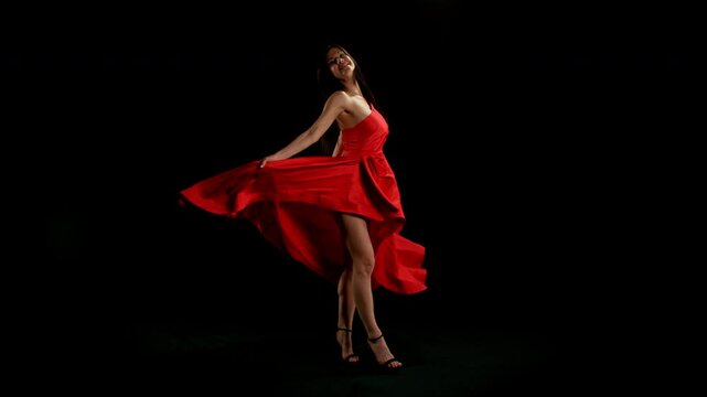 Brunette Woman in Ruby Red Dress Posing Against a Black Background . Filmed on High Speed Cinematic Camera in Super Slow Motion
