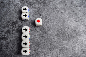 Wooden blocks or dice with arrows with one moving forward and standing out from the crowd. Concept...