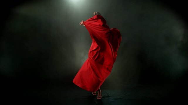Brunette Woman in Ruby Red Dress Posing Against a Black Background . Filmed on High Speed Cinematic Camera in Super Slow Motion