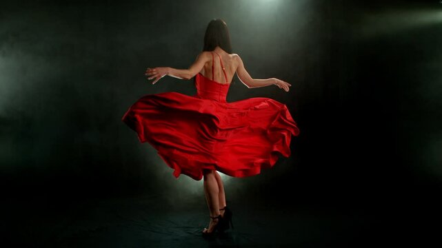 Brunette Woman in Ruby Red Dress Posing Against a Black Background . Filmed on High Speed Cinematic Camera in Super Slow Motion