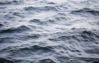 Fototapeta premium A close-up view of rippled ocean water. Gentle waves create a textured surface of varying shades of gray-blue