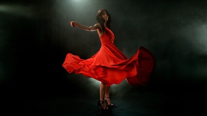 Brunette Woman in Ruby Red Dress Dancing Against a Black Background , Freeze Motion