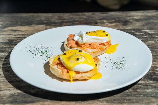 Egg benedict or poached egg with salmon on white plate. Isolated by wooden background or table. Food photography