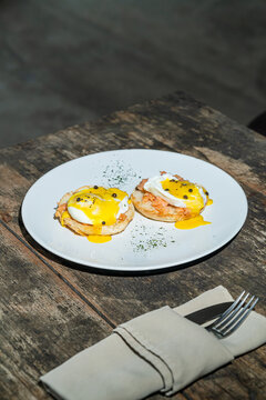 Egg benedict or poached egg with salmon on white plate. Isolated by wooden background or table. Food photography