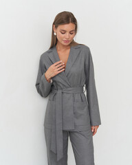Stylish female model showcases trendy gray outfit in a modern studio setting