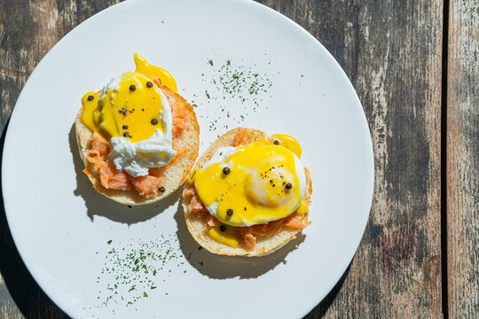 Egg benedict or poached egg with salmon on white plate. Isolated by wooden background or table. Food photography