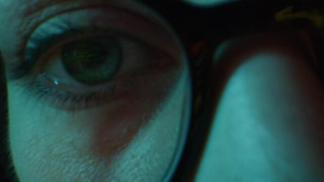 Close up of tired woman working at night on laptop, girl in eye glasses with reflections overworking busy, using computer in dark office