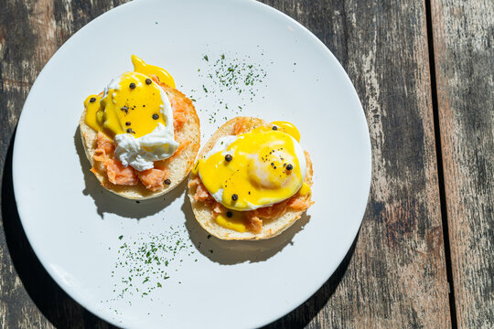 Egg benedict or poached egg with salmon on white plate. Isolated by wooden background or table. Food photography