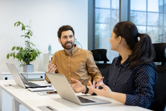 A candid moment captured as two colleagues engage in a lively conversation during a meeting, showcasing teamwork.