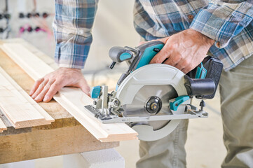 A skilled craftsman operates a circular saw on a wooden plank, showcasing precision and...