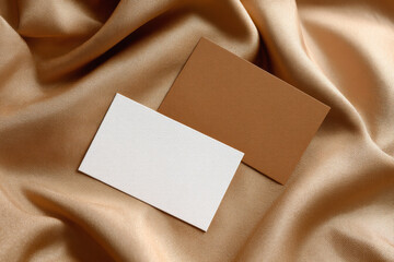 Two blank business cards on golden silk fabric background, elegant and minimal design