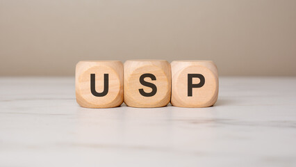 Wooden cubes forming the acronym USP on a white table.