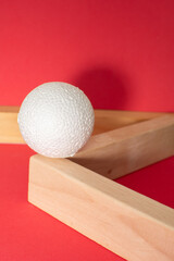 Still life with wooden blocks and a a plastic foam ball on red background	