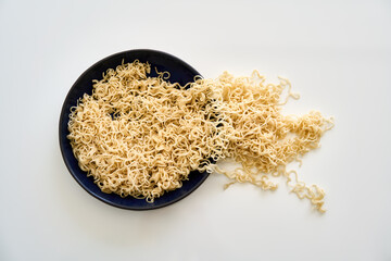 Cooked instant noodles overflow and spill from full bowl into table