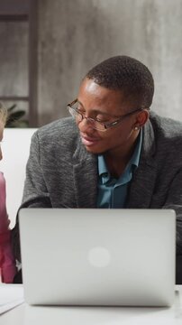 African-American English native speaker tutor gives task to brother and younger sister students at laptop computer in living room slow motion