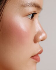 Close-up profile of a young woman with glowing skin against a neutral background highlighting her natural beauty
