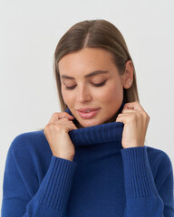 Elegant fashion shoot featuring a woman in a stylish blue sweater in a studio setting