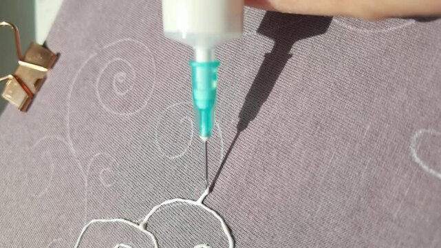 Female hand drawing with 3d pen on fabric, creating intricate patterns in a closeup sequence.
