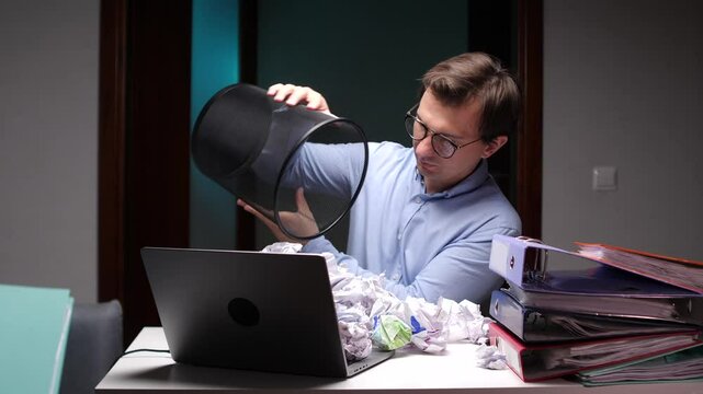 Frustrated office worker emptying wastebasket on laptop keyboard