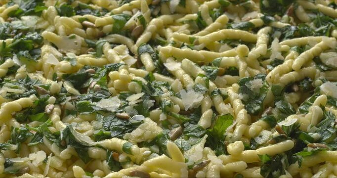 Ligurian cuisine: Trofie al Pesto. Trofie pasta with roughly chopped pesto, background texture. Table spin. 